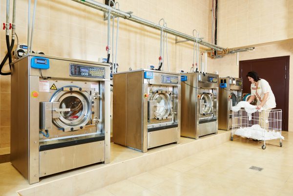 cleaning services. Woman loading laundry washing machine